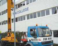 Cherry Picker parked outside of Preston College as workers use the basket to apply the sign