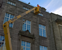 Worker using a Cherry Picker to work on the top of a tall building