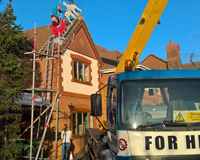 Man using Cherry Picker to install Christmas decorations on the roof of a home